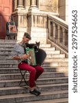 Small photo of Paris, France - September 01, 2023: Street musician plays accordion with black cat on the stairs of Sacre Coeur Basilica in Montmartre