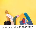 International Day of people with Down Syndrome, 21. march. Feet of a little boy with Down syndrome, his sister, mother and father on a yellow background with different colors socks. Flat lay concept.