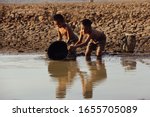 Small photo of An Asian boy in a dry area is using a plastic bucket to draw water from the final water source. Concept of shortage of clean water from global warming