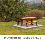 Wooden seat in a park. Picnic in the park. Rest in the open area. Wooden picnic table and seats. Street view, travel photo, nobody, selective focus