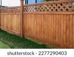 Nice new wooden fence around house. Wooden fence with green lawn. Street photo, nobody, selective focus