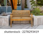 Wooden bench in the city park. Recreation area with empty contemporary wooden benches. Public city resting area design. A wooden bench on concrete floor. City improvement, urban planning, public space