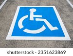 Reserved parking sign for handicapped. Disabled parking space with white blue painted sign of handicapped parking spot. Handicapped parking spot, blue square on asphalt. Accessibility concept.