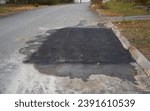 Small photo of resurfacing street road surface with patched asphalt, pavement after construction