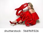 Valentine's Day. Word love letters from the inflatable. Girl holding a big word love.
Girl with retro hairstyle in red dress in red high heels sitting on the floor in studio on a white background.
