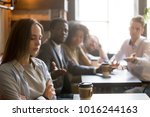 Small photo of Multiracial friends trying to make peace with insulted girl offended after bad joke, diverse young people apologizing aggrieved resentful drama queen woman sitting apart sulking at meeting in cafe