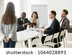 Small photo of Angry african boss pointing on wristwatch reprimanding employee coming too late at diverse team meeting, tardy unpunctual worker scolded by executive, discrimination and punctuality at work concept