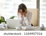 Stressed tired businesswoman feels exhausted sitting at office desk with laptop and crumpled paper, frustrated woman can not concentrate having writers block, lack of new ideas or creative crisis
