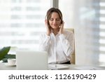 Relaxed businesswoman listening music in headphones at work break, young smiling employee wearing headset feels no stress free enjoying calming audio tracks playing on laptop application or online