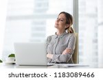 Smiling businesswoman sitting in office chair relaxing with eyes closed, calm female worker or woman ceo feeling peaceful resting at workplace dreaming about positive things distracted from work