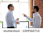 Small photo of Mad male colleagues have disagreement in office arguing on work issues, furious millennial employee point at coworker blaming for mistake or failure, businessman accuse partner disputing at workplace