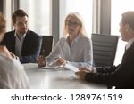 Serious middle aged businesswoman talks at group board executive meeting, confident mature old female leader speaking discussing work offers solution negotiating with partners at corporate briefing
