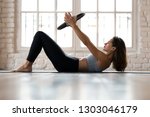 Young sporty attractive woman doing toning pilates exercise for abs with exercise circle, crunches for abdominal strengthening using pilates magic circle, wearing sportswear at yoga studio or at home