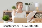 Small photo of Excited happy woman sitting at desk working at home with paper documents holding in hands, received good news, smart female student feel proud and joyful after finished coursework, graduate work