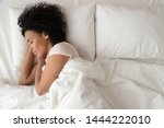 Serene calm african american woman sleeping in comfortable bed lying on soft pillow orthopedic mattress, peaceful young black lady resting covered with blanket on white sheets in bedroom, top view