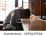 Small photo of Depressed drunk young addicted man drinker sleeping alone on bar counter with whiskey glass, sad guy alcoholic passed out after drink too much alcohol addiction abuse, intoxication alcoholism concept