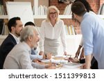 Small photo of Multi-ethnic team members takes part in briefing lead by aged businesswoman company boss, businesspeople feels satisfied succeed agreement acceptable to both parties, mentoring or negotiations concept