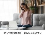Small photo of Tired young woman touch stiff neck feeling hurt joint back pain rubbing massaging tensed muscles suffer from fibromyalgia ache after long computer work study in incorrect posture sit on sofa at home