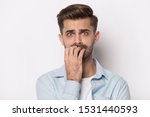 Small photo of Close up headshot portrait of scared millennial caucasian man isolated on grey studio background bite nails feel frightened, anxious worried young male look terrified afraid, panic attack concept