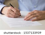 Small photo of Close up young businessman sitting at table, filling in questionnaire, financial document, bank loan form. Successful male entrepreneur signing contract agreement, putting signature on franchising.