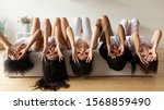 Small photo of Five funny diverse girls wear pyjamas lying on bed upside down grimacing looking at camera, happy young multi ethnic women having fun in bedroom enjoying pajama slumber sleepover party together