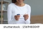 Small photo of Woman sit indoors close up focus on hands holding pregnancy test smiling waiting result, feels happy about long-awaited gestation confirmation, check ovulation day using modern digital device concept