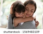 Close up gorgeous sisters different age hugging closed eyes enjoy moment of tenderness feels happy, mother and little daughter cuddling having strong bonds, adopted kid new mom reunification concept
