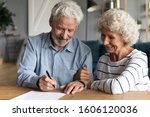 Small photo of 60s elderly spouses at lawyer office sitting at desk hoary husband holding pen family ready sign marriage contract make legal formalities at notary, bequeath savings and property to children concept