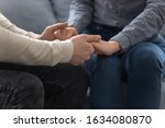 Close up view young loving couple seated together on couch holding hands, gesture symbol of care and sincere feelings, declaration of love and marriage proposal, support protection of soulmate concept