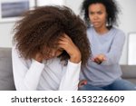 Small photo of Upset african american teenage girl feeling sad turned back to angry strict black mother scolding lecturing difficult kid for bad behavior, mad mom arguing shouting at stubborn child teen daughter