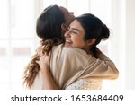 Candid diverse girls best friends embracing standing indoors, close up satisfied women face enjoy tender moment missed glad to see each other after long separation, friendship warm relations concept