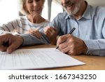 Small photo of Close up of 60s husband and wife sit at desk sign health insurance contract close deal, smiling old mature couple spouses put signature on document make good agreement, elderly healthcare concept