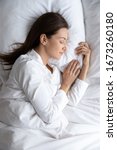Small photo of Top above view vertical image tranquil young brunette woman in pajamas lying under duvet on comfortable orthopedic mattress, sleeping on soft pillow, enjoying sweet dreams good night rest in bed.