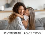 Affectionate beautiful young woman cuddling small preschool child daughter, feeling happiness. Cute little kid girl embracing loving mommy, feeling thankful, enjoying tender sweet time at home.