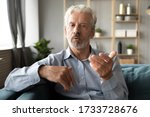 Confident hoary middle aged handsome man looking at camera, holding business talk with clients partners online. Web camera view mature senior grandfather chatting with friends family via video call.