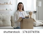 Small photo of Close up woman sit on sofa near big cardboard box full of new clothes, old stuff used apparels is prepared for donation. Help for poor needy people, humanitarian aid, charity and benevolence concept