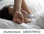 Close up sleepless young woman lying in bed, suffering from insomnia, tired exhausted female covering face with hand, trying to sleep, resting under white warm duvet on soft pillow