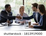 Small photo of Smiling diverse businesspeople shake hands get acquainted greeting at team meeting in office. Happy multiracial male colleagues employees handshake at briefing with coworkers. Acquaintance concept.