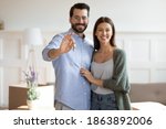 Small photo of Portrait of happy Caucasian young couple renters show house keys buy first shared dwelling together. Smiling man and woman tenants move relocate to own new home. Realty, rent, relocation concept.