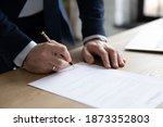 Close up businessman signing contract, making successful purchasing or investment deal, filling legal document, candidate employee signing job agreement after interview, standing at office desk