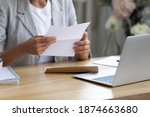 Getting news by mail. Close up of young lady involved in paperwork at home office studio hold paper letter in hands. Businesswoman get message out of envelop read information from bank client supplier