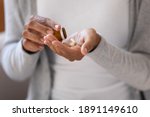 Small photo of Close up young african ethnicity biracial woman pouring pills from bottle, taking daily dose of complex vitamins or prescribed medicine antibiotics, reducing painful feelings or strengthen immunity.