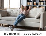 Full length calm woman with closed eyes resting on cozy couch, leaning back, enjoying lazy leisure time, attractive peaceful young female relaxing, daydreaming, taking nap on sofa at home