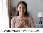 Small photo of Portrait of happy millennial female volunteer holding folded hands on chest, looking at camera. Kind smiling young woman feeling thankful, showing appreciation, gratitude believe charity concept.