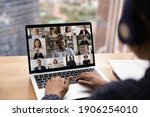 Small photo of Over shoulder view of female in headset take part in distant virtual briefing video conference using laptop. Young woman employee meet with diverse colleagues online discuss work affairs on quarantine