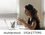 Profile view close up woman in headphones chatting online, using laptop, teacher leading lesson, recording webinar, explaining, teaching students, distance education, businesswoman consulting client