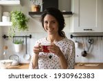 Excellent taste. Headshot portrait of happy housewife taking break from domestic work enjoying natural fresh brewed black tea. Smiling young lady look at camera hold cup of hot drink at cozy kitchen