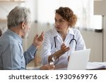 Small photo of Young Caucasian female doctor in white uniform consult senior male patient at meeting in private clinic. Caring woman GP talk speak with mature man at consultation in hospital. Geriatrics concept.