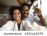 Head shot portrait overjoyed African American married couple showing keys, happy wife and husband, homeowners or tenants making selfie, purchased first dwelling, new apartment, mortgage concept