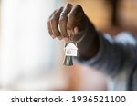 Small photo of Welcome to new house. Close up of young african american man hand hold bunch of keys. Cropped shot of black guy real estate agent realtor give offer you client key from home flat apartment. Copy space